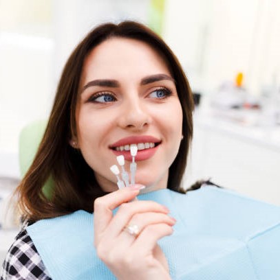 Girl chooses color of veneers at the dentist office Veneers